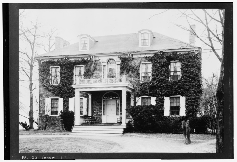 A black and white photograph of the historic Fort Hunter Mansion, a stone building covered in ivy with white columns